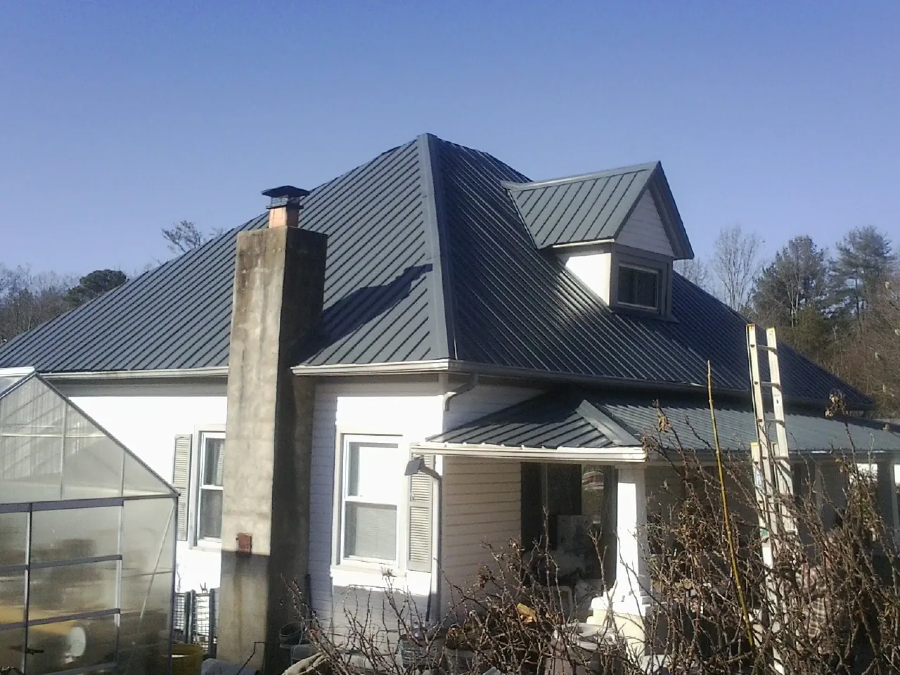 Dark blue standing seam metal roof on a white farmhouse with dormer — Slate & Tile Roof Repair by Roofing Brothers in Fort Mitchell
