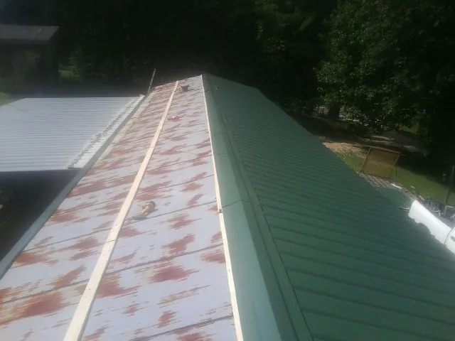 Old rusted panels beside newly installed green metal roofing — Wind Damage Roof Repair by Roofing Brothers in Fort Mitchell