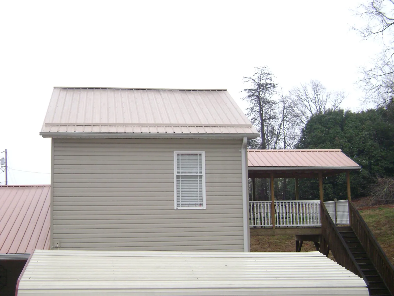 Tan metal roofs on a two story addition and attached porch, from a Roof Replacement job in Fort Mitchell