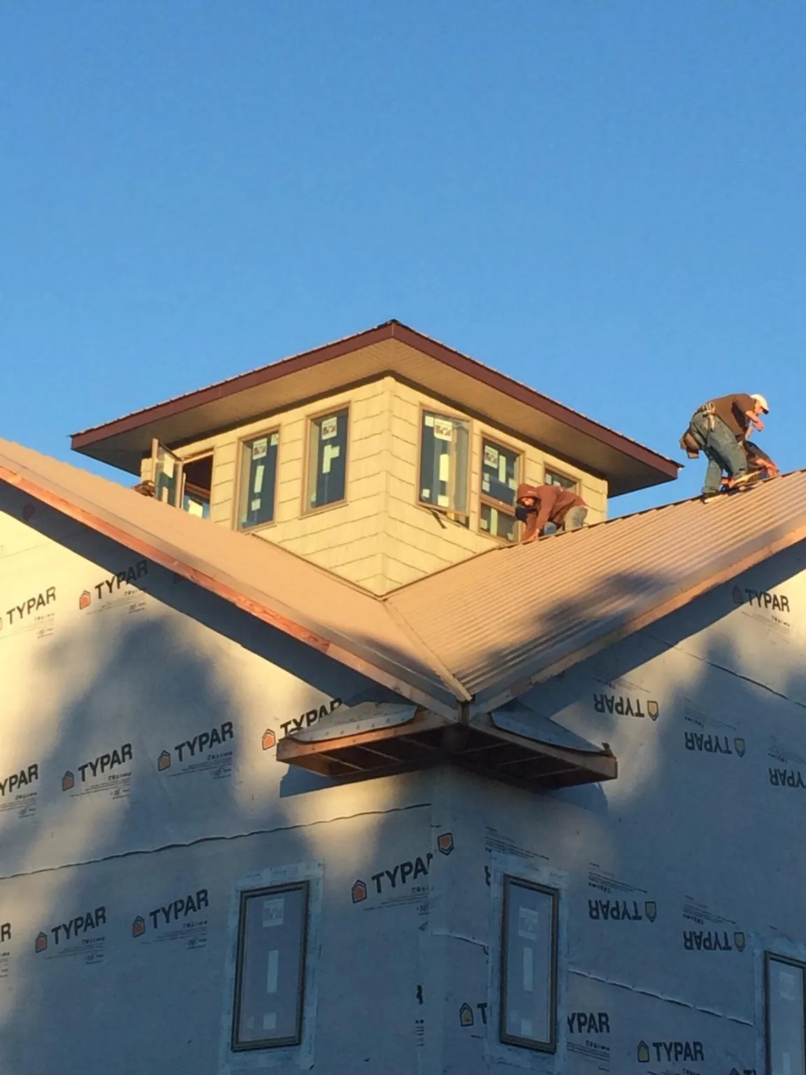 Roofers working around a rooftop cupola on a new metal roof at sunset — Roof Waterproofing in Fort Mitchell by Roofing Brothers